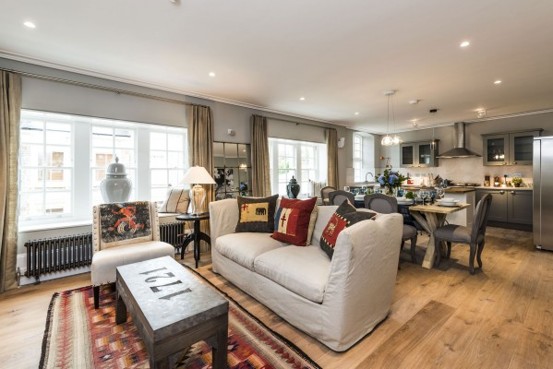 Open-plan living room and kitchen with a cream sofa, patterned rug, large sash windows and recessed ceiling lights